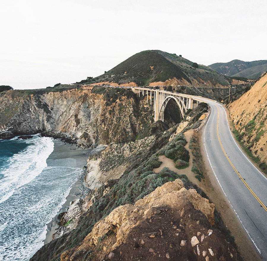 A view of Highway One on the California coast, with a bridge spanning a creek flowing into the ocean